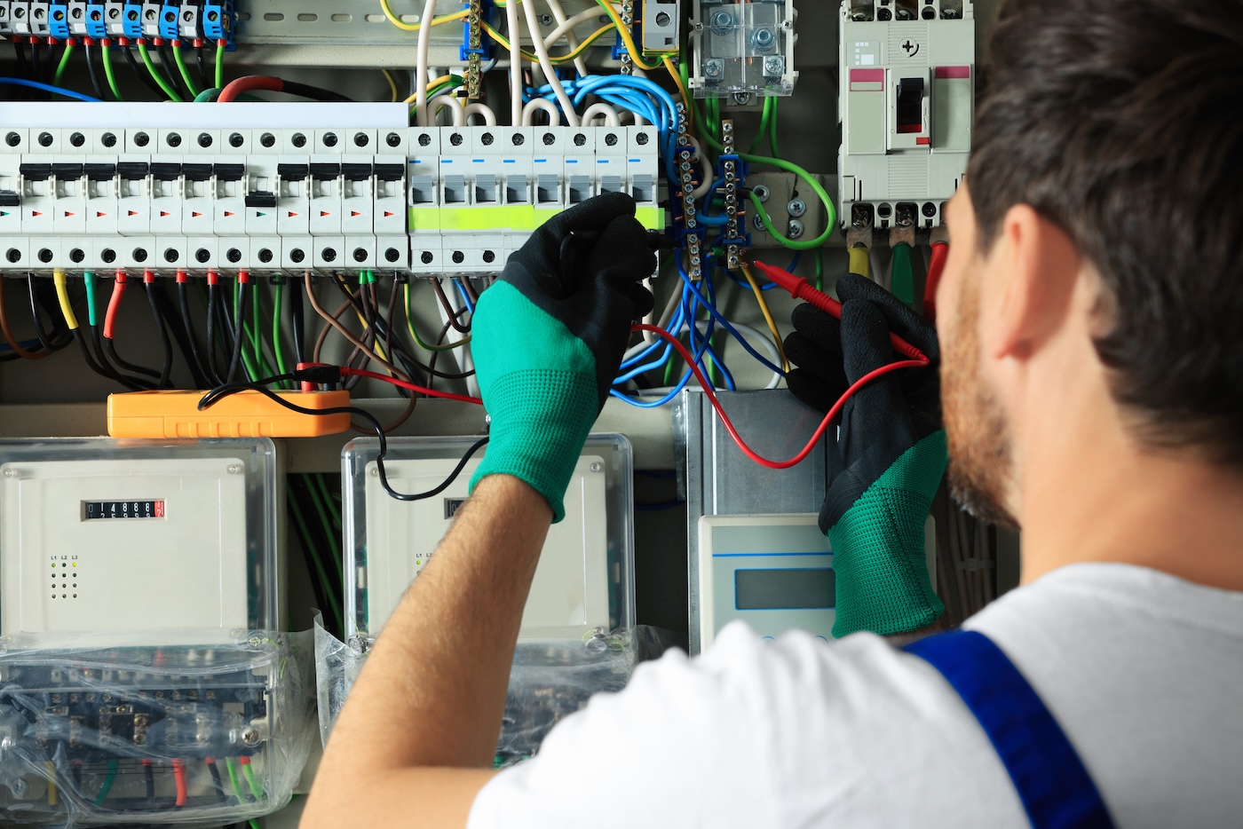 Electrician checking electric current with multimeter indoors, closeup