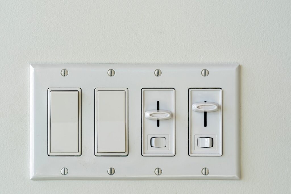 A fixture of mixed rocker switches and light dimmers installed on a white wall
