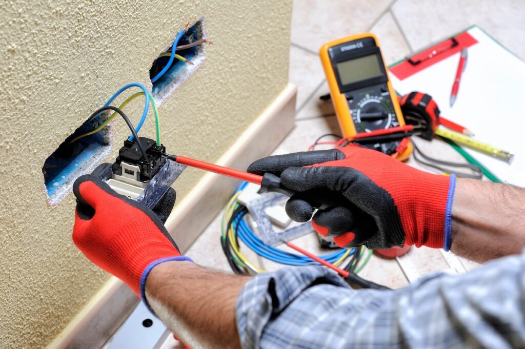 Electrician technician at work blocks the cable between the clamps of a socket in a residential electrical installation