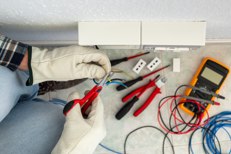 Electrician worker at work with scissors prepares the electrical cables of an electrical system.