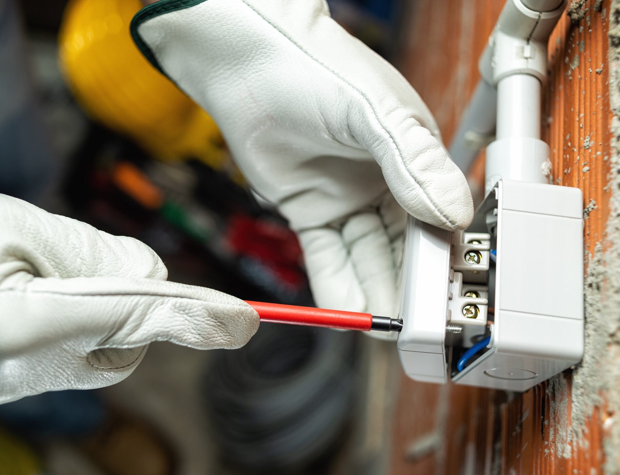 Electrician worker with screwdriver installs the switches of a residential electrical system.