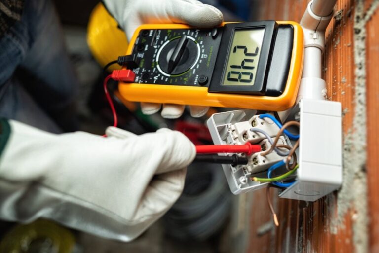 Electrician worker at work with the tester measures the voltage in a switch of a residential electrical system.