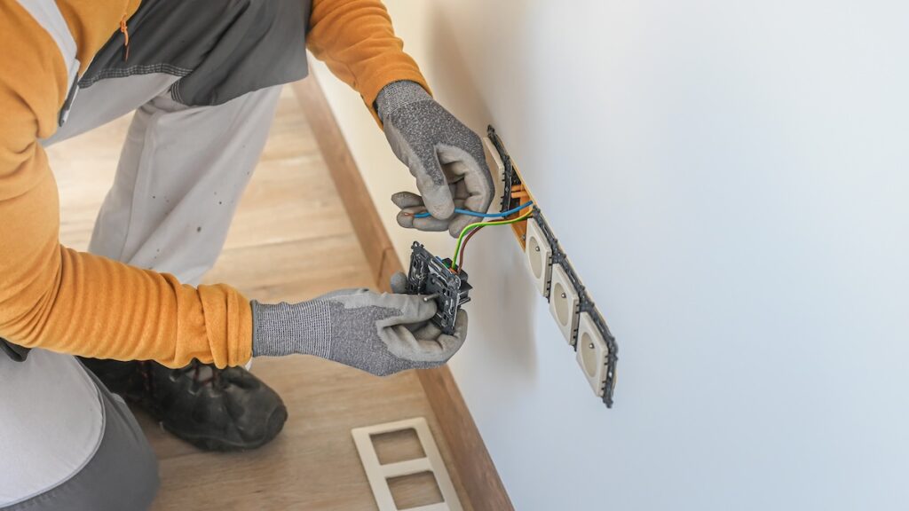Electrical installation. An electrician during installation a wall sockets to multi pack socket. 