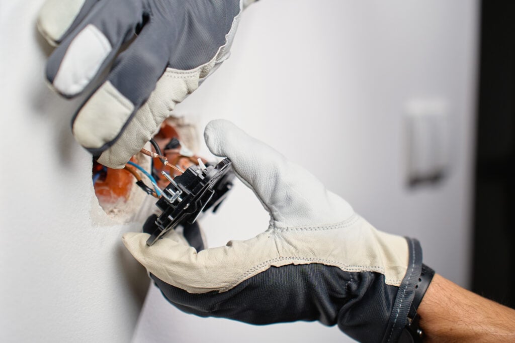 how to fix loose outlets Electrician hands wearing protective gloves connecting exposed copper electrical wires to wall light switch. Concept of electrical safety, professional repair, home renovation and maintenance