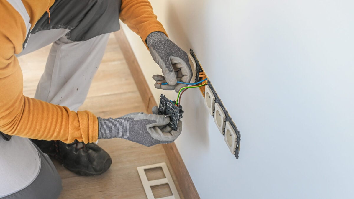 how to fix loose outlets Electrical installation. An electrician during installation a wall sockets to multi pack socket. Hands and sockets out of focus.