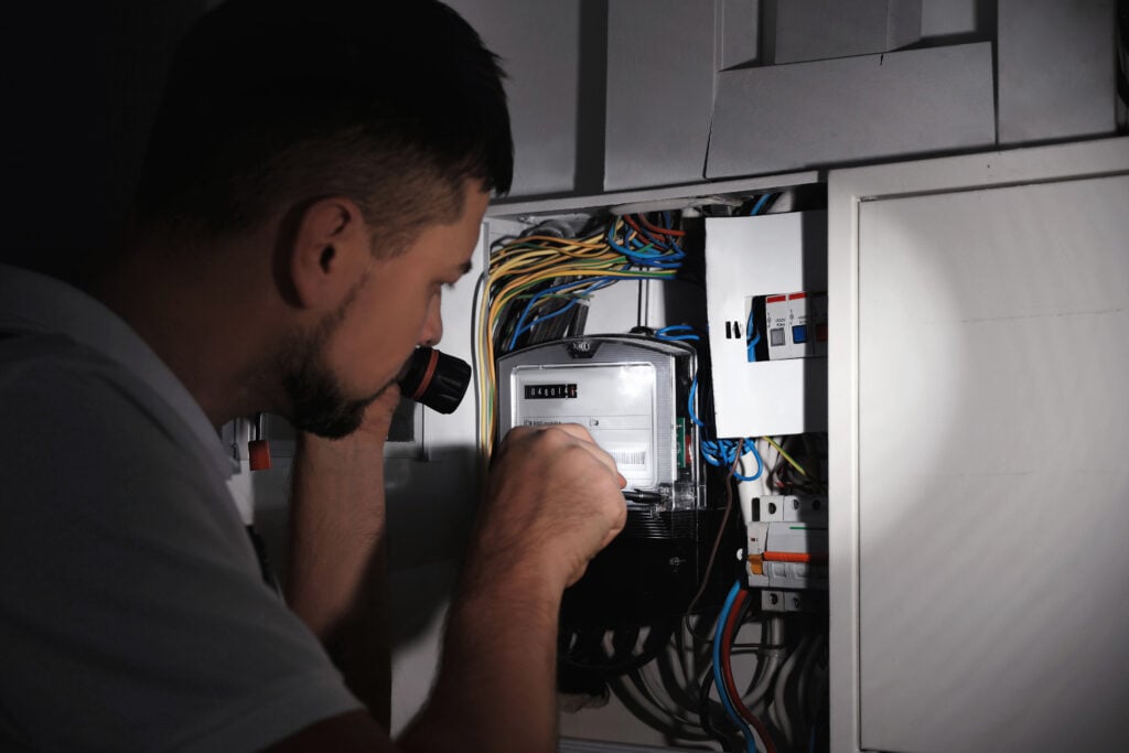 how to wire a breaker box Electrician with flashlight fixing electric panel indoors