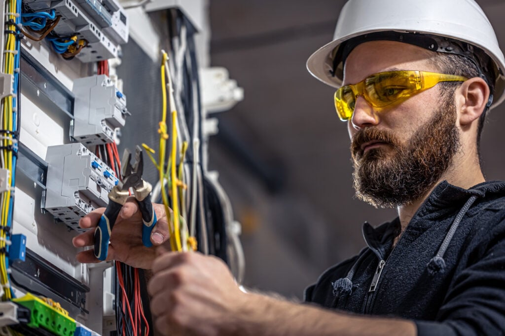 what does a fuse do Male electrician at the checkout counter on a blurred background of a switchboard.