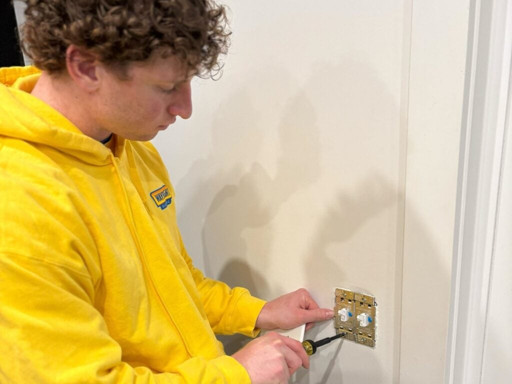 why do my lights keep flickering worker using yellow hoodie adjusting outlets